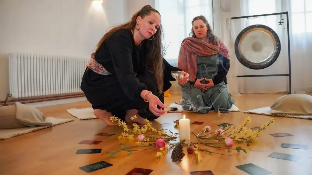 Frauen sitzen im Kreis auf dem Boden eines hellen Raums